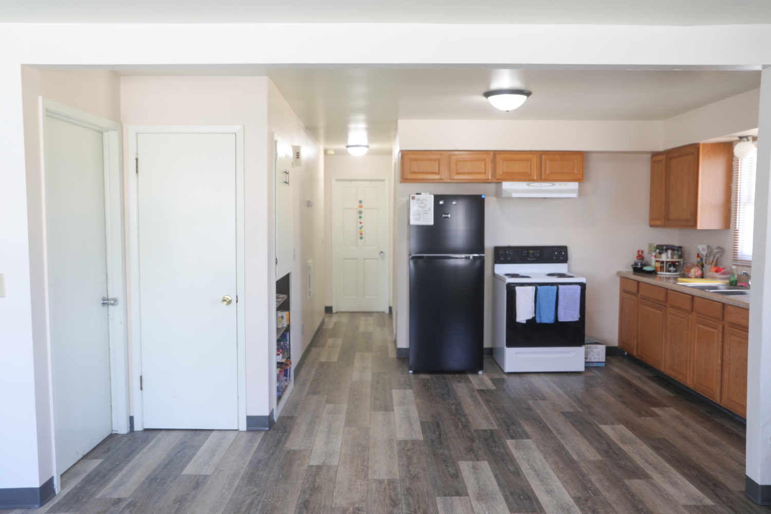 Duplex kitchen, with a black fridge, brown cabinets, and an oven.