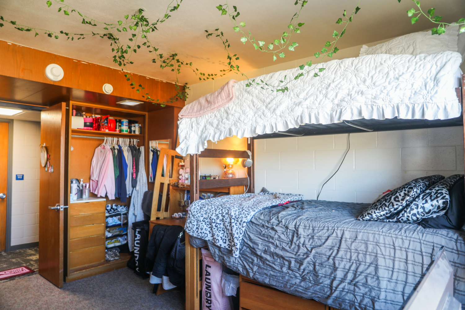 Dorm room with bunk beds, a closet, and a desk.